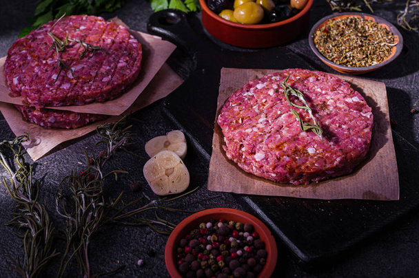 Raw pork hamburger cutlet with spices on a dark background. Home production of semi-finished products. Simple food. - Фото, изображение