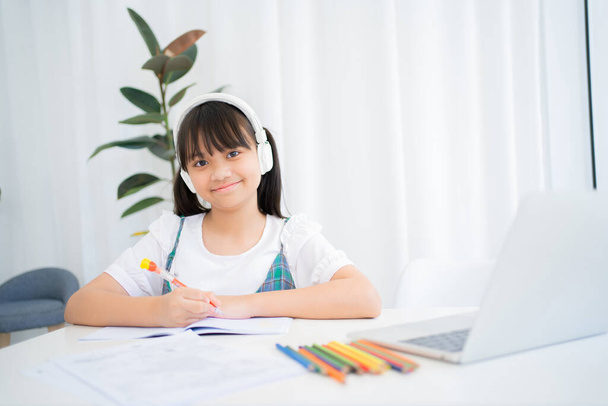 Маленькая девочка учится дома онлайн. Она счастлива.. - Фото, изображение
