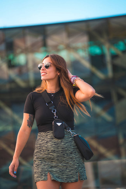 Beautiful young caucasian brunette businesswoman outside the green glass office building background. Portrait of the girl with sunglasses - Φωτογραφία, εικόνα