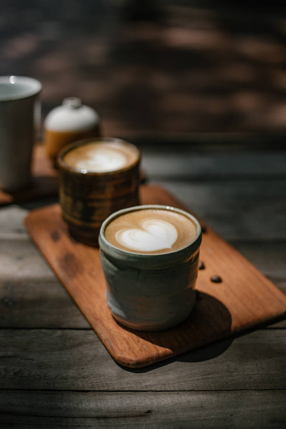Taza selectiva del foco del café caliente del arte del latte en la mesa de madera, foco en foa blanco - Foto, imagen