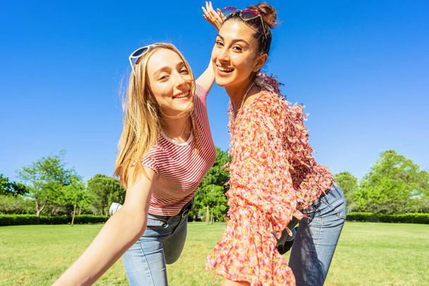 Két nő legjobb barátai szórakozás egy városi parkban pózol egy boldog szelfi mosoly nézi a kamerát. Két homoszexuális diáklány, akik élvezik a változatosságot együtt viccelődnek a természet zöldjében. - Fotó, kép