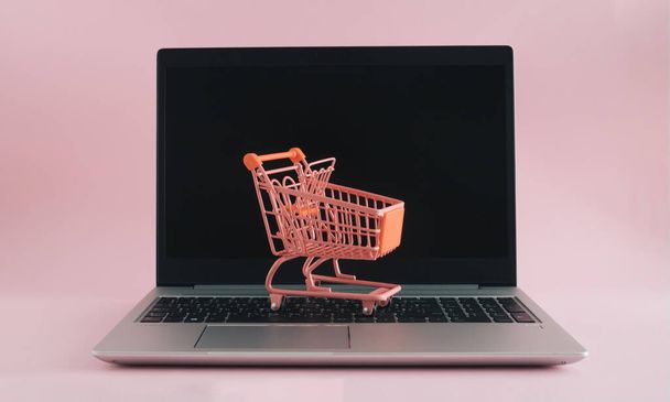 Shopping cart on laptop. Minimal online shopping concept - Photo, Image