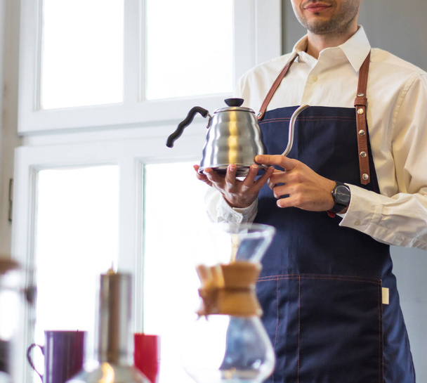 muž v zástěře barista drží konvici na kávu - Fotografie, Obrázek