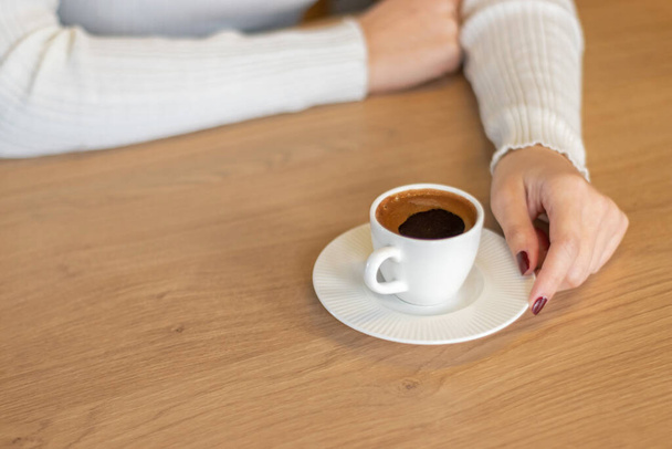 La donna sul tavolo di legno che tiene il caffè turco con le mani - Foto, immagini