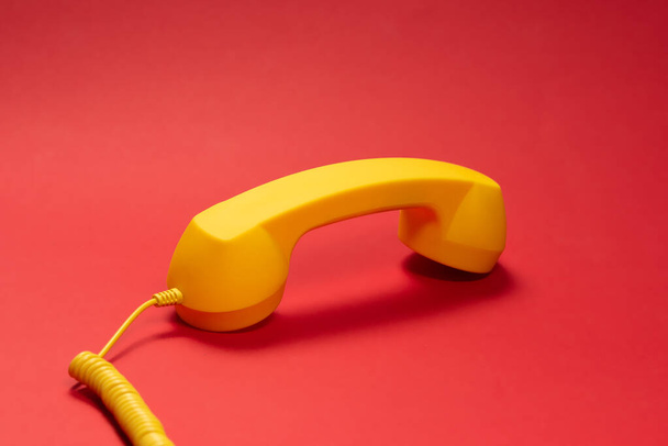 Yellow handset on red background. Copy space.  - Photo, image