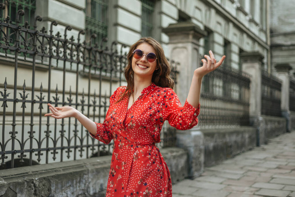 Jovencita alegre con vestido rojo de verano y gafas de sol, retrato de mujer bonita en verano en las calles de la ciudad - Foto, Imagen