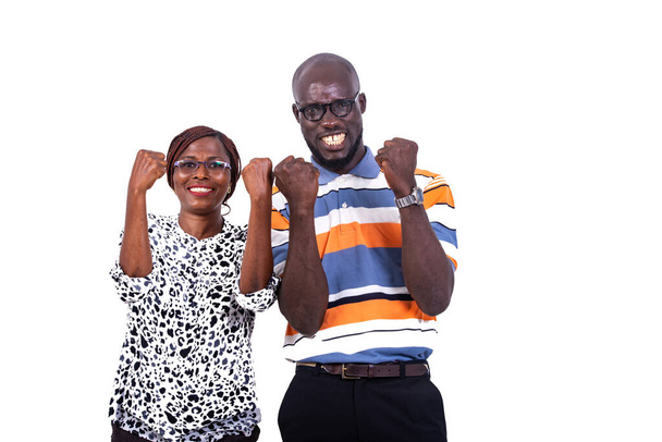 a couple in glasses standing on a white background showing victory gesture and looking at the camera laughing. - Foto, imagen