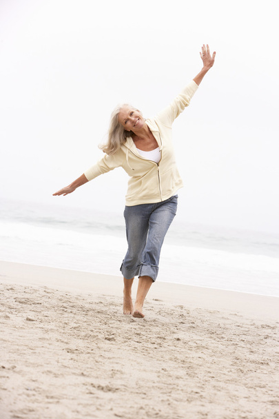Senior Woman On Holiday Running Along Winter Beach - Photo, image