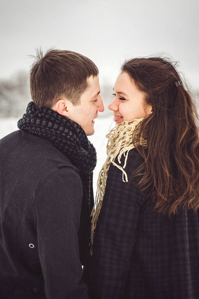 Mies ja tyttö lämpimissä vaatteissa ja huiveissa kävelyllä lumisessa metsässä ja pellolla. - Valokuva, kuva