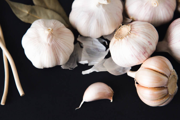 Garlic bulbs on black background, close-up. Organic garlic. Food background. Copy space. Selective focus. - 写真・画像