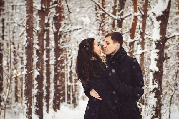 A guy and a girl in warm clothes and scarves on a walk in the snowy forest and in the field - Fotografie, Obrázek