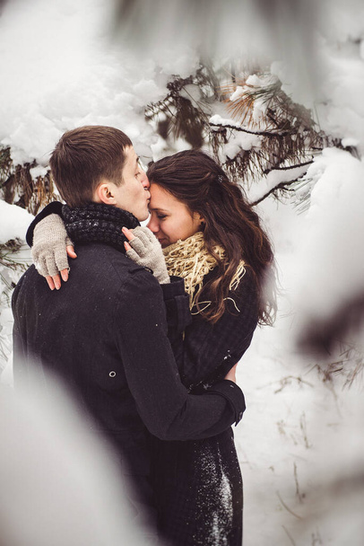 Парень и девушка в теплой одежде и шарфах на прогулке в снежном лесу и в поле - Фото, изображение