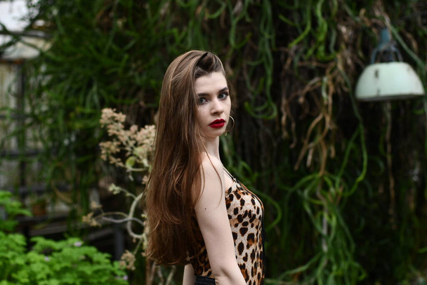 Αρκετά κομψό κορίτσι σε λεοπάρδαλη φόρεμα σε εξωτικό κήπο - Φωτογραφία, εικόνα