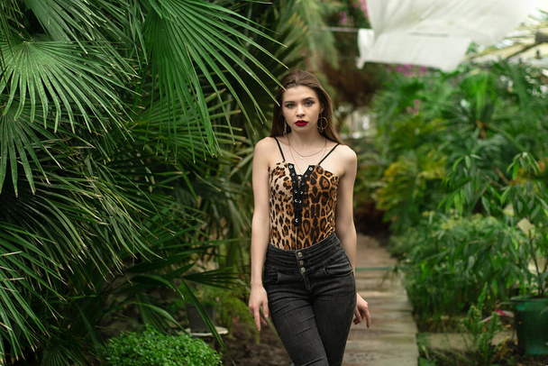 Pretty stylish girl in leopard dress in exotic garden - Фото, изображение