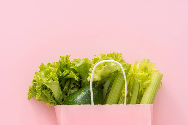 健康的な食品の背景を提供します。ピンクの背景に紙の袋の野菜でビーガン菜食主義者の食品.美食ショッピング食品スーパーマーケットときれいな食事の概念.トップ表示. - 写真・画像