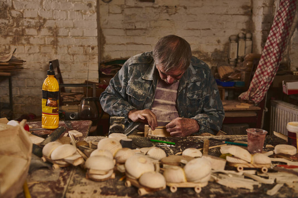 Artista de madera, artesano, carpintero en un taller para la fabricación de juguetes de madera hechos a mano. Juguetes ecológicos seguros para niños - Foto, Imagen