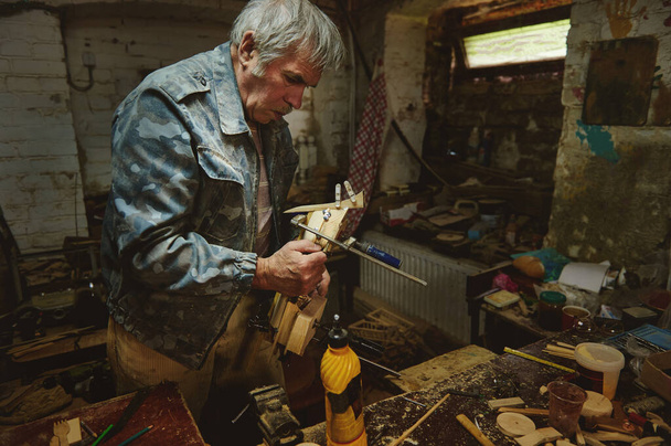 Starší muž tesař v akci ve své dílně. Řemeslníci, umělci v akci, talent, dovednosti a hobby koncepty - Fotografie, Obrázek