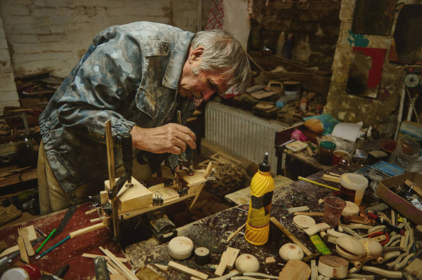 Puinen veistos taiteilija työskentelee tehdä malli puinen lelu, käsintehty puinen purjevene - Valokuva, kuva