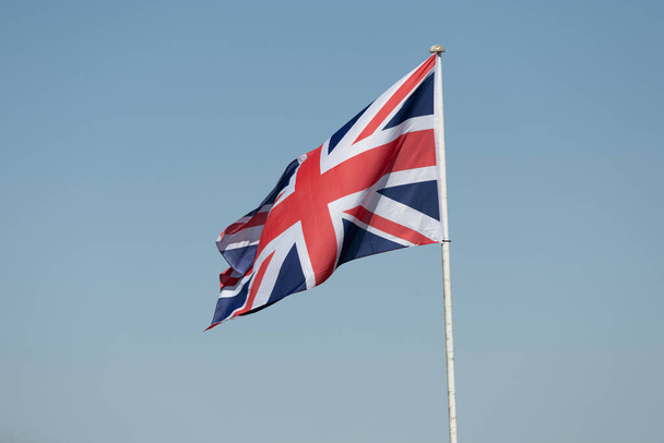 Una fotografía de la bandera del sindicato en un mástil que sopla suavemente en el viento. Tomado contra un cielo claro azul claro - Foto, Imagen