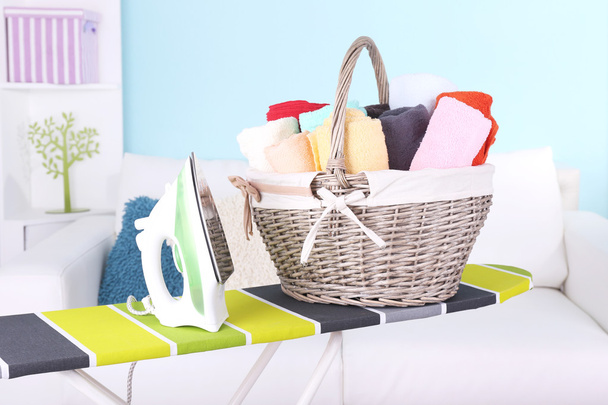 Basket with laundry and ironing board on home interior background - Foto, afbeelding