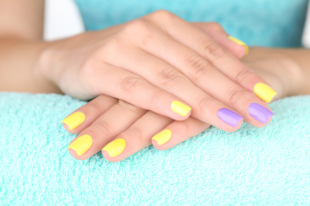 Female hand with stylish colorful nails, on color towel, close-up - Φωτογραφία, εικόνα