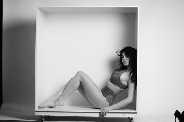 belle femme brune portant de la lingerie posant en cube blanc au studio  - Photo, image