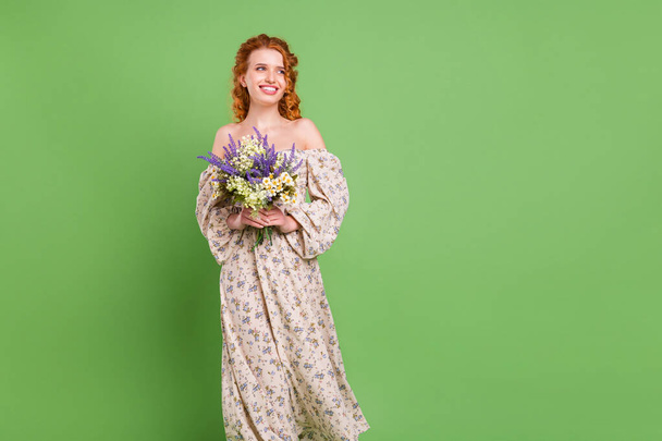 Photo of charming happy joyful lady look empty space good mood smile hold bouquet isolated on green color background - Фото, зображення