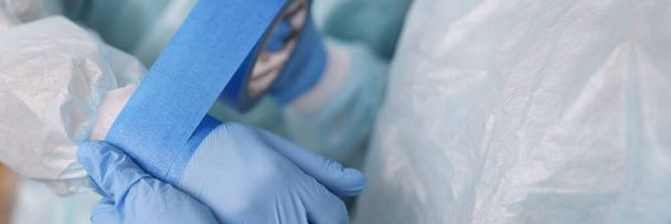 Nurse gluing tape on sleeve of surgical suit closeup - Fotografie, Obrázek