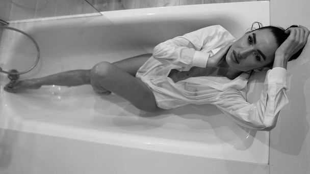 kaunis nuori nainen mies paita poseeraa kylpyhuoneessa, musta ja valkoinen kuva - Valokuva, kuva