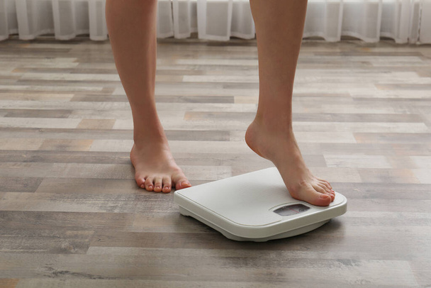 Woman stepping on floor scales indoors, closeup. Weight control - Zdjęcie, obraz