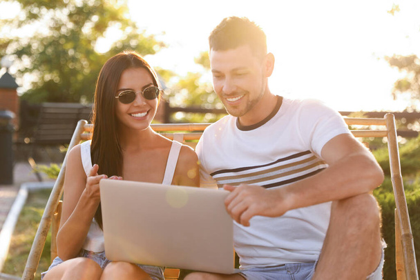 Happy couple with laptop resting together outdoors - Фото, зображення