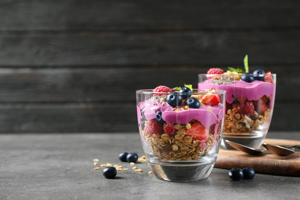Tasty dessert with acai smoothie, granola and berries on grey table. Space for text - Фото, изображение