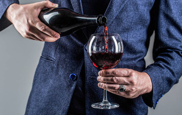 Офіціант наливає червоне вино у склянку. Сомельє людина, дегустація, виноробня, чоловічий винороб. Червоне вино наливають з пляшки на склянку. Пляшка для гастрономічного напою, келих червоного вина, сомельє, дегустація
 - Фото, зображення