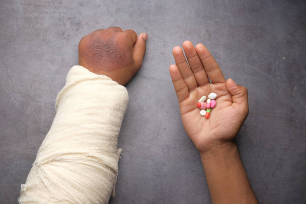 main douloureuse blessée avec bandage et pilules médicales à portée de main  - Photo, image