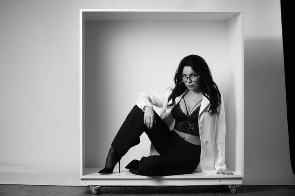 bela morena mulher vestindo lingerie e calças com camisa branca posando em cubo no estúdio  - Foto, Imagem