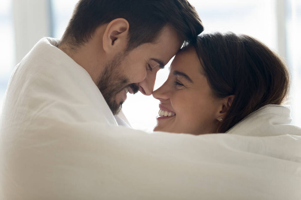Mixed race couple cuddling touch foreheads covered in warm blanket - Foto, Bild