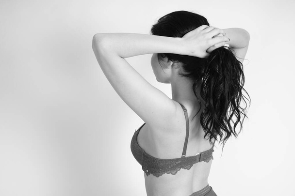 mooie brunette vrouw dragen lingerie poseren in wit kubus in studio  - Foto, afbeelding