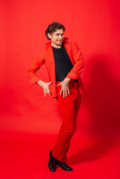 Portrait of a tall handsome man dressed in red shirt posing on the red background. - Foto, afbeelding