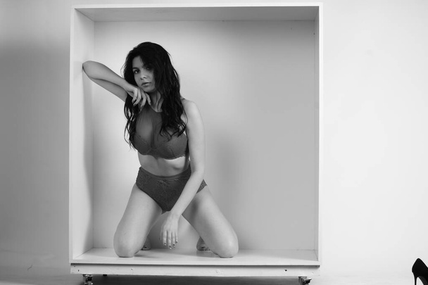 bela morena mulher vestindo lingerie posando em cubo branco no estúdio  - Foto, Imagem