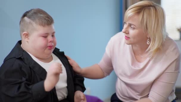 Beziehung zu Kind mit Behinderungen, fürsorgliche Lehrerin tröstet weinende männliche Kinder - Filmmaterial, Video