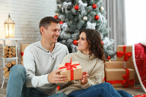 Man presenting Christmas gift to his girlfriend at home  - Foto, afbeelding