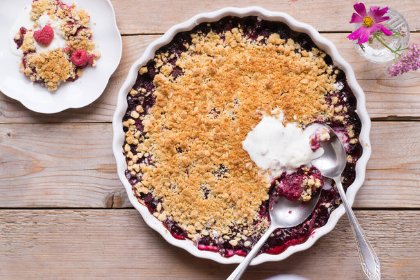 Raspberry and peach crumble on wooden table - 写真・画像