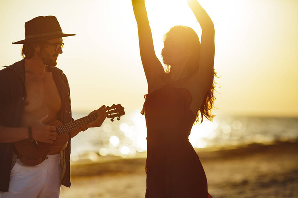 Para zakochanych gra na gitarze i tańczy na plaży - Zdjęcie, obraz