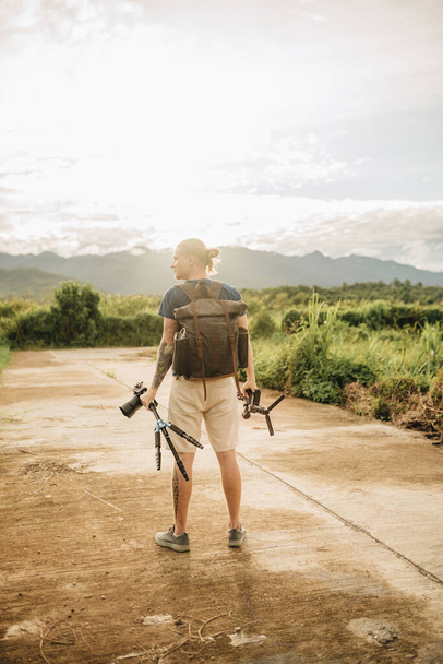 Man videographer is standing on a road at sunset in Pai Thailand - Foto, afbeelding
