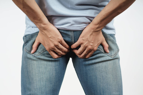 Young Man holding his bottom because Diarrhea, Hemorrhoids, constipation. Health care and medical concept - Photo, Image