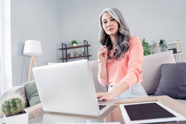 Portrait of attractive smart focused grey-haired woman using laptop creating presentation typing at home house flat indoor - Фото, изображение