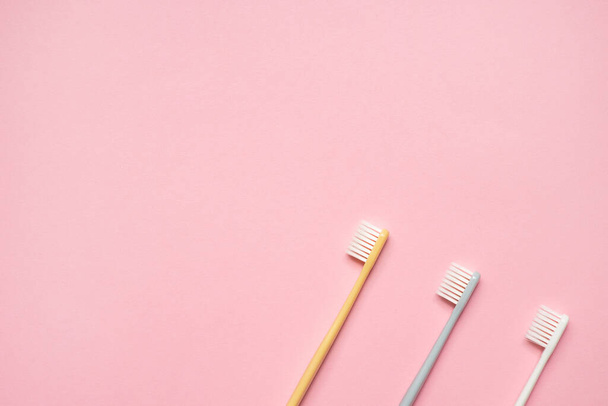 Gray and white toothbrushes on pink background.Taking care of teeth, dental concept. Flat lay photo, copy space, top view. - Photo, image