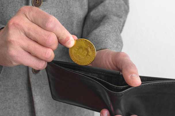 Hombre de negocios vistiendo un traje, sosteniendo una cartera y una moneda de oro Bitcoin BTC criptomoneda, nuevo concepto de dinero virtual. Tecnología minera o blockchain - Foto, Imagen