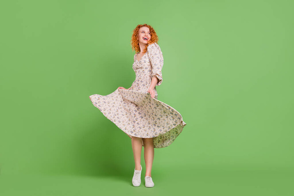 Full length photo of dreamy funky young woman look empty space fly skirt dance isolated on green color background - Foto, immagini