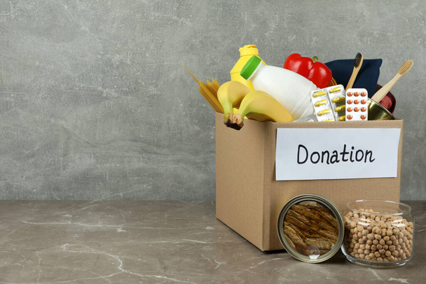 Concepto de donar con caja de donación en mesa texturizada gris - Foto, Imagen